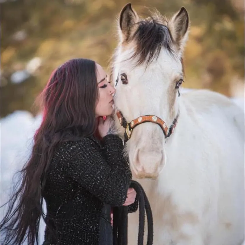 Jenna resting her forehead against her grey horse